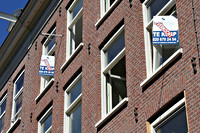 Borden te koop aan een rij appartementen in de de Pijp, Amsterdam