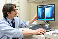 Medisch specialist achter een pc scherm met röntgen foto’s
