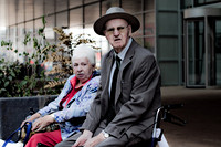 Twee oudere mensen in een rolstoel en op een rollator